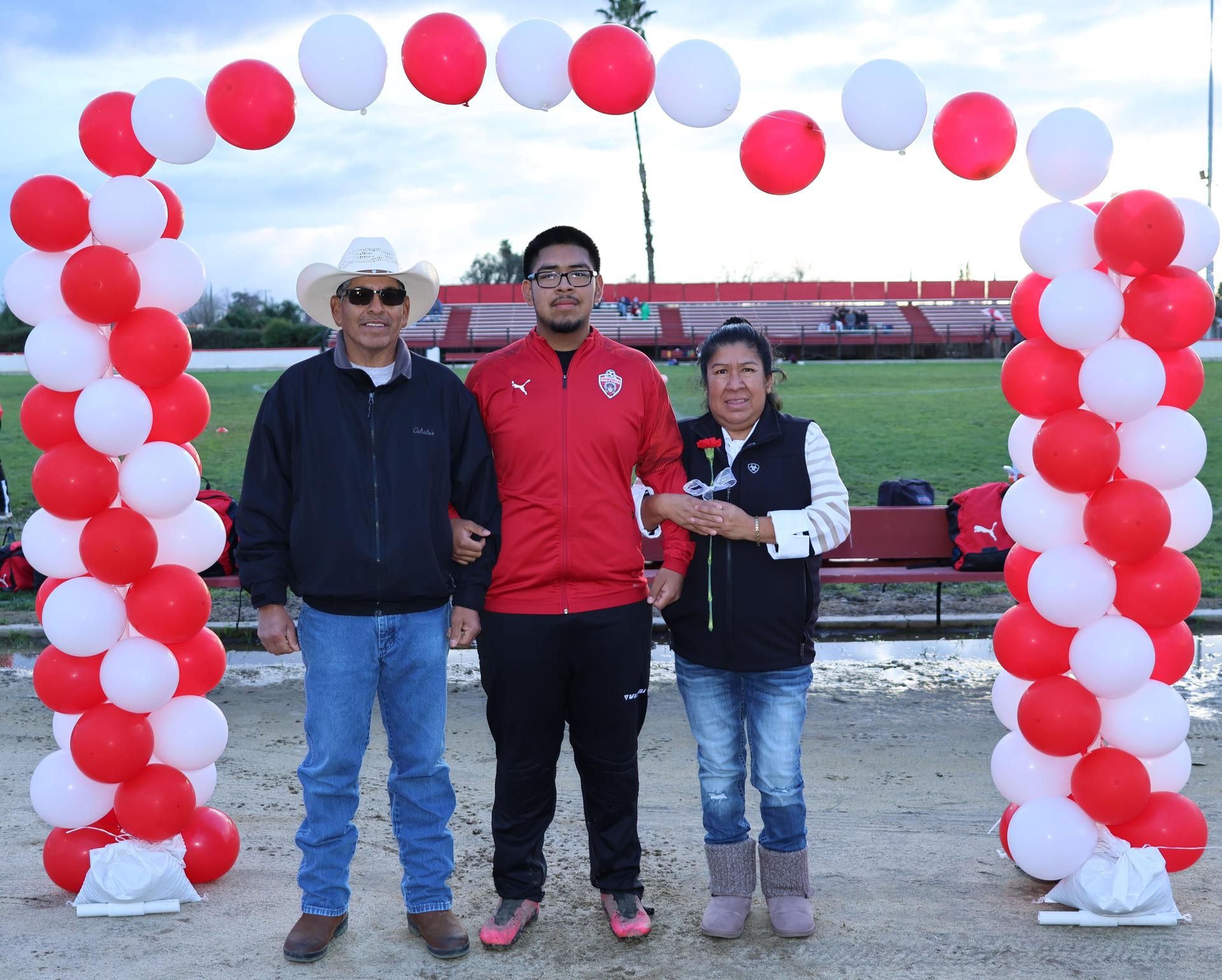 seniors and their escorts posing beneath a balloon arch