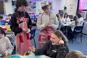 a student gives her order to two other students who hold notepads and wear aprons
