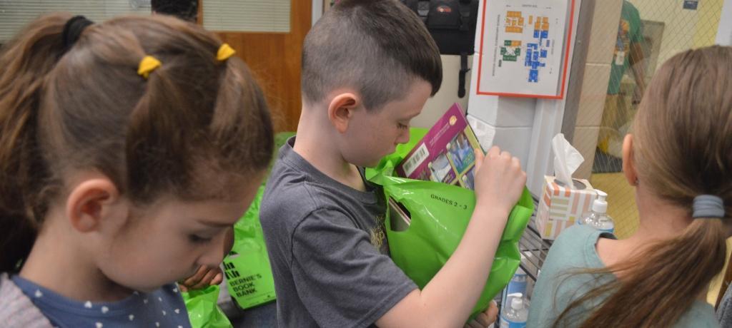 boys inspects contents of his book bag