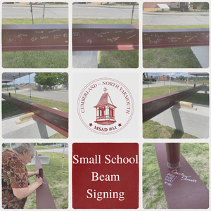 Community members signing a beam at a school event, with names and drawings visible.