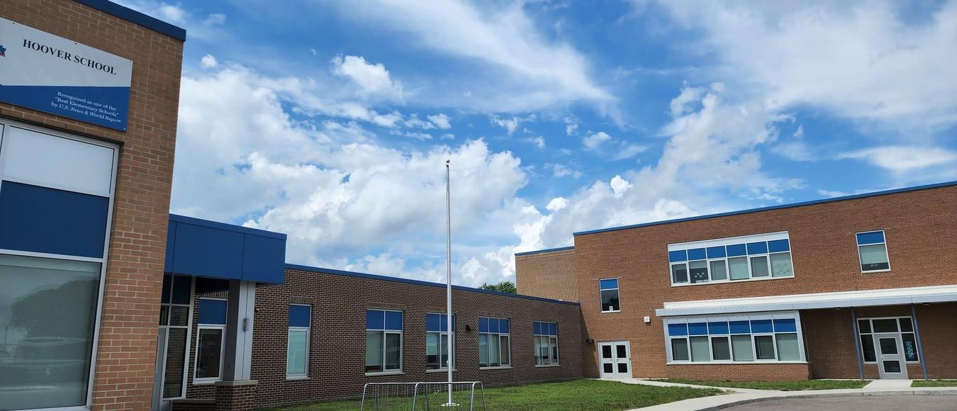 Hoover School brick building exterior with blue trim accents under a bright, cloudy blue sky.