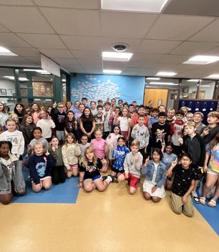 A large group of children and adults gathered in a school hallway.