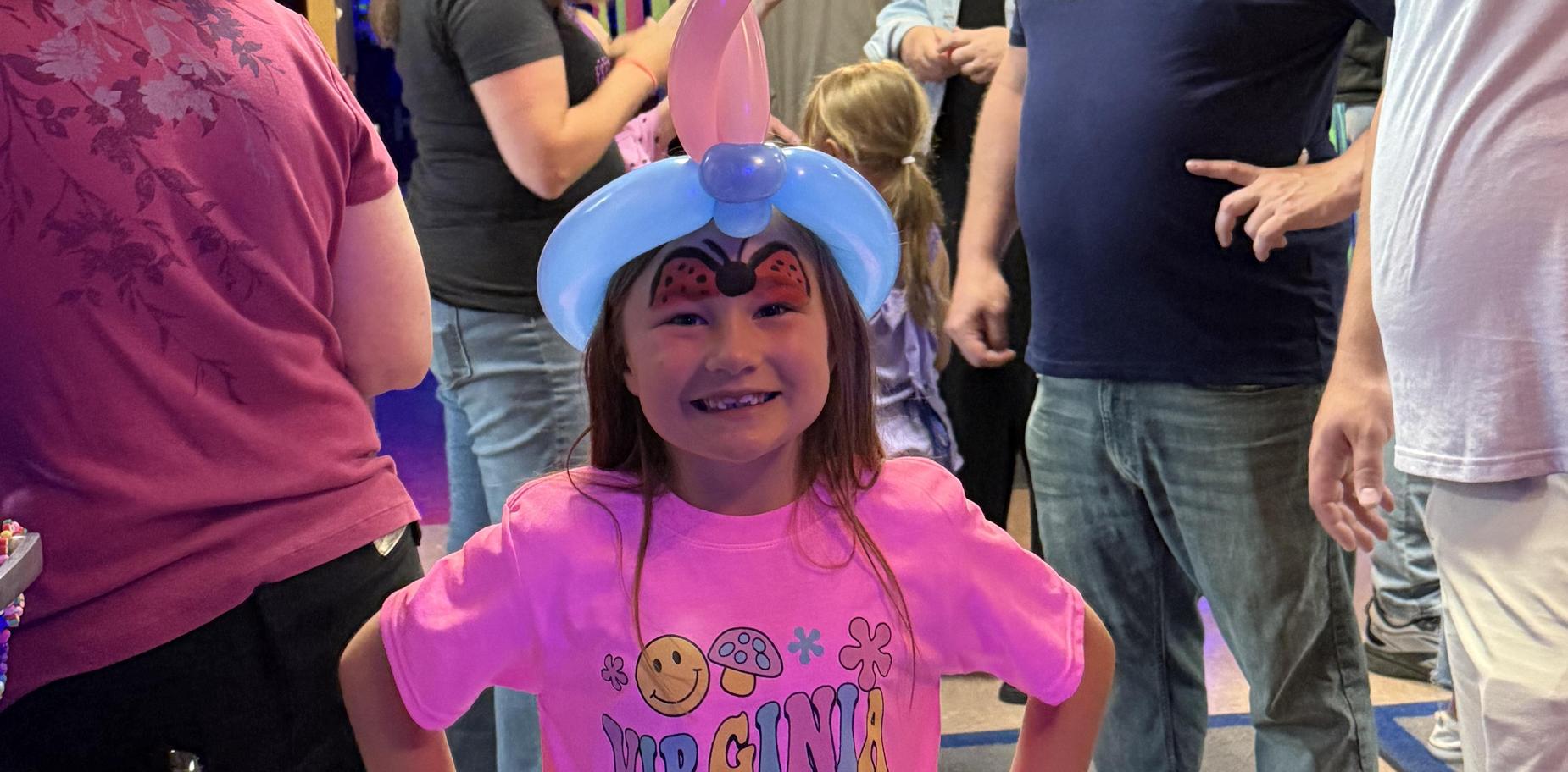 girl wearing a balloon hat and smiling