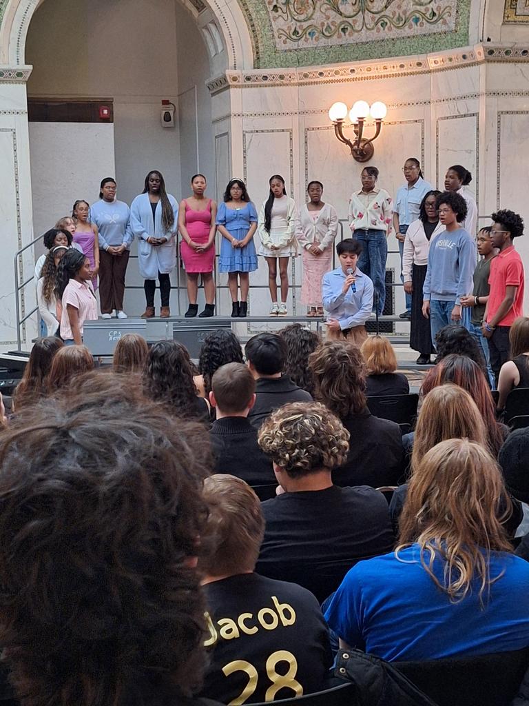 Choir singing in front of seated crowd.