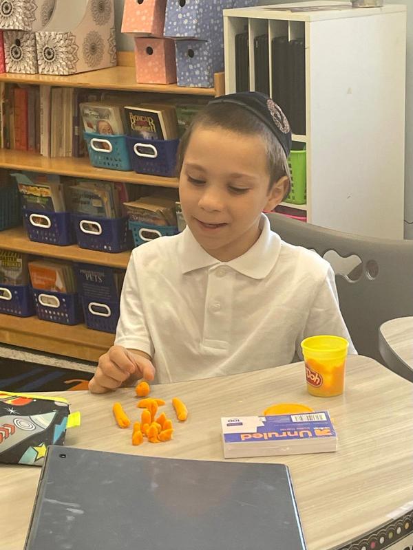 A third grade boy sculpts with playdough.