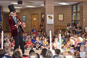 An adult dressed as a rock n roll star performs for students