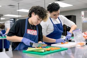 two MHS culinary students chopping veggies.