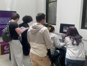 Group of people using computers in a library space.