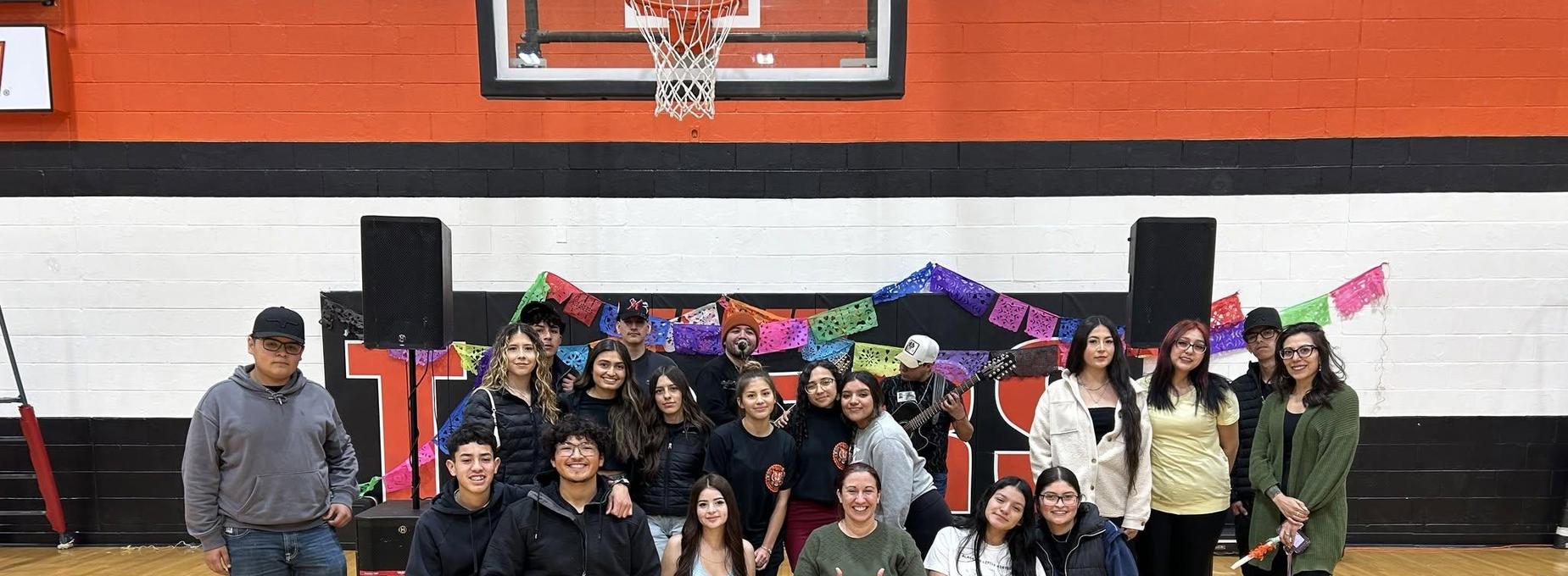 Group of students posing together at a school event decorated with colorful banners.