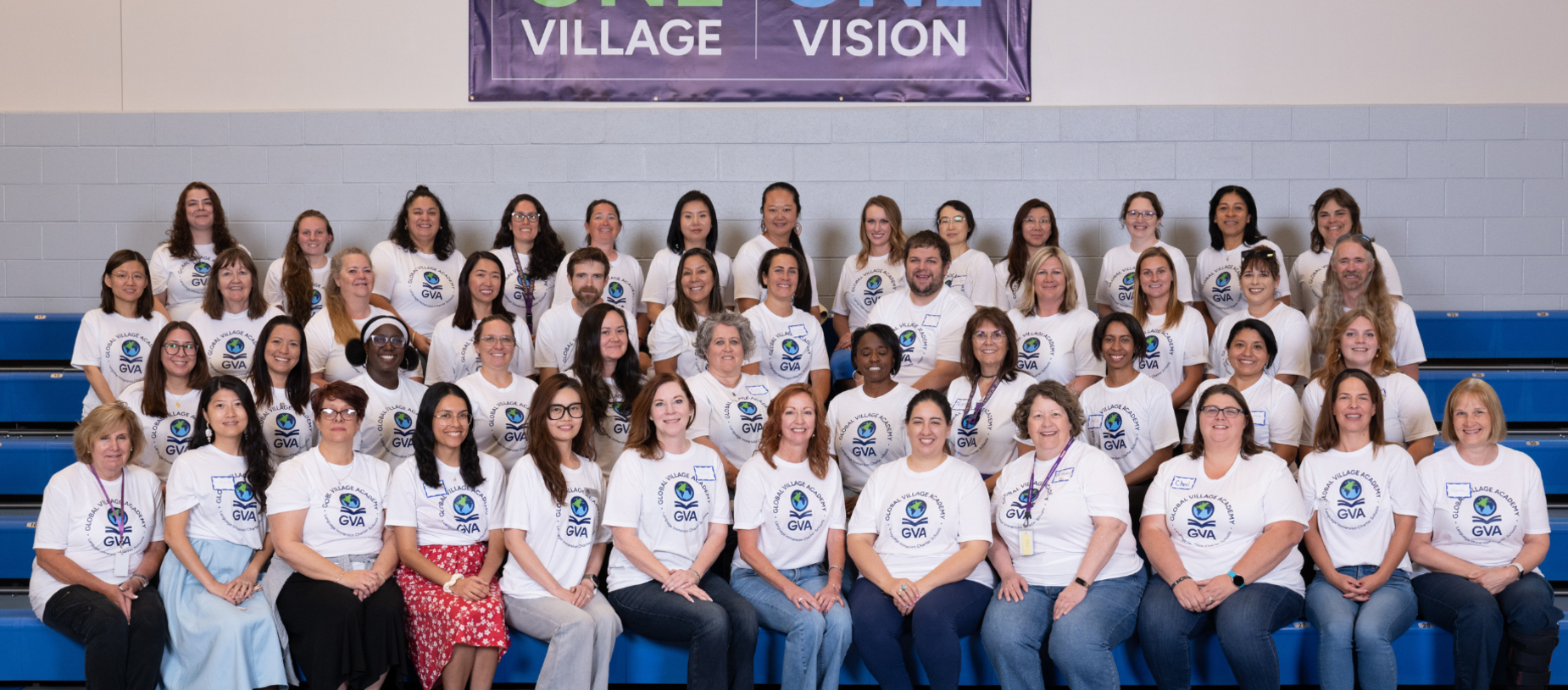 Group photo of diverse individuals in matching shirts, sitting on bleachers.