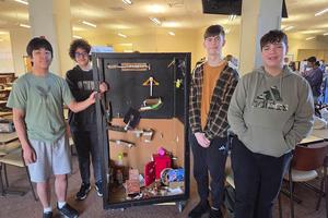 photo of students on the team standing next to their chain reaction machine