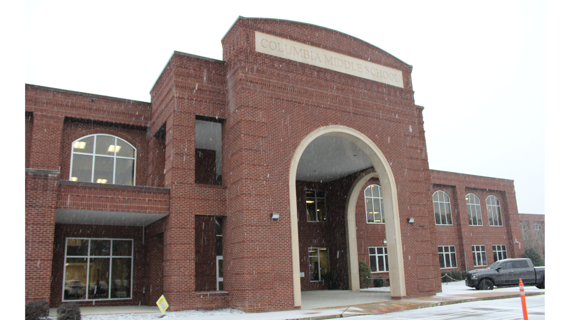 Brick building of Columbia Middle School with snow falling.