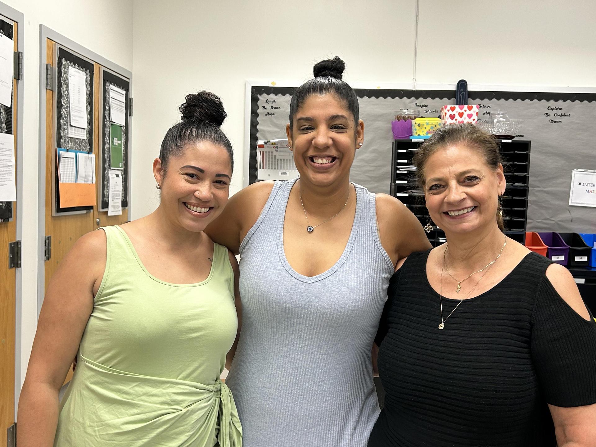 Three women standing next to each other in office. 