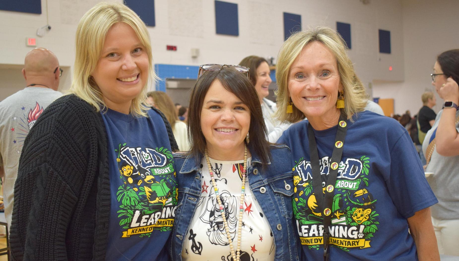 Three women posing together, smiling at a social event.