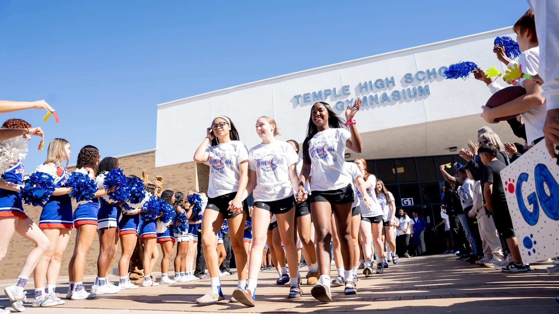 Cheerleaders and students welcome teammates at Temple High School gym entrance.