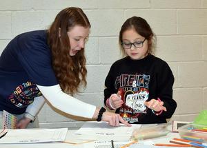 a college student helping a girl complete a writing activity
