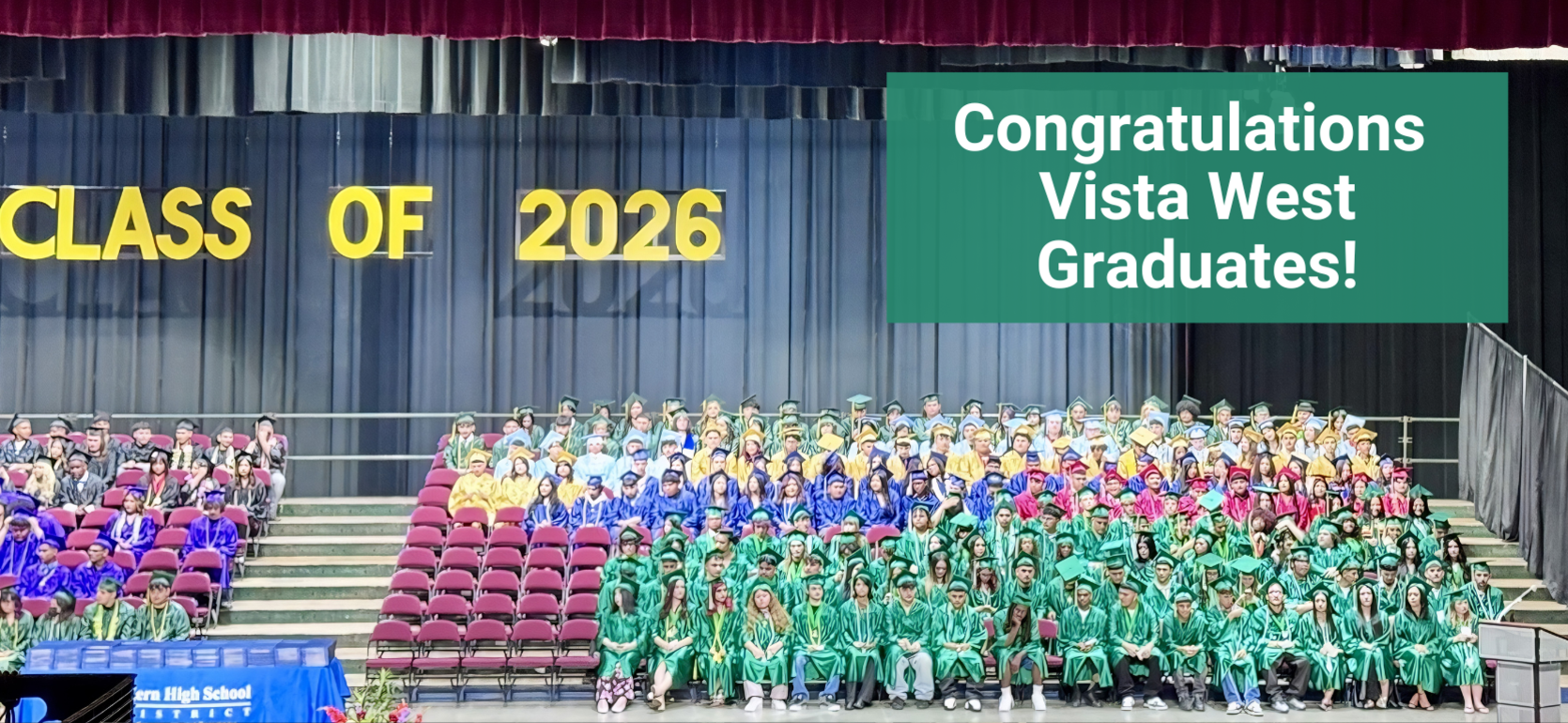 Graduating class of 2026 with many students in colorful gowns at a ceremony.