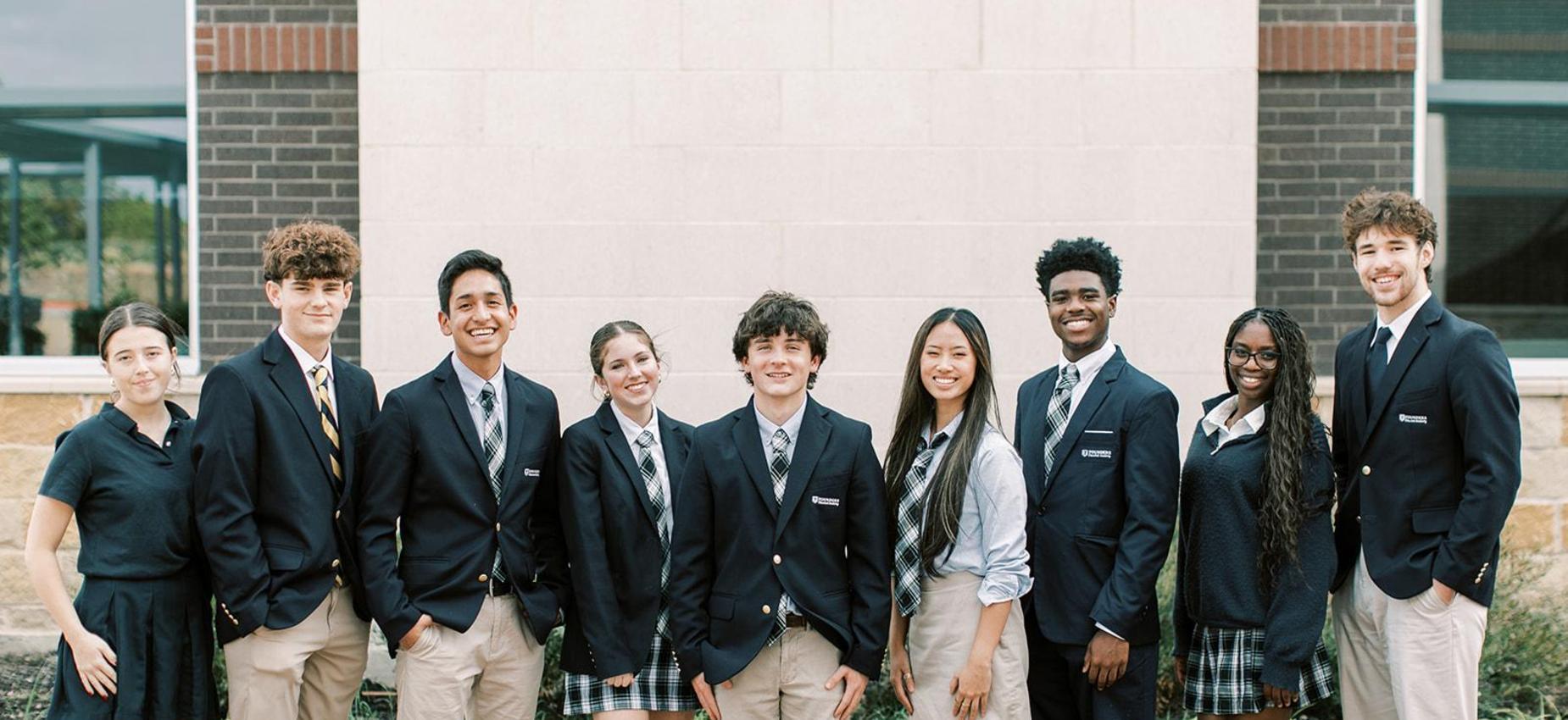 High school students in navy blazers stand together outside