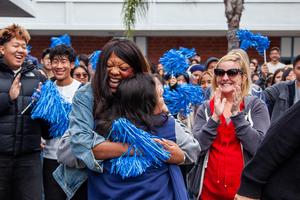Rebecca Chai hugs a Walnut High School colleague in excitement as staff and students around them clap and celebrate.