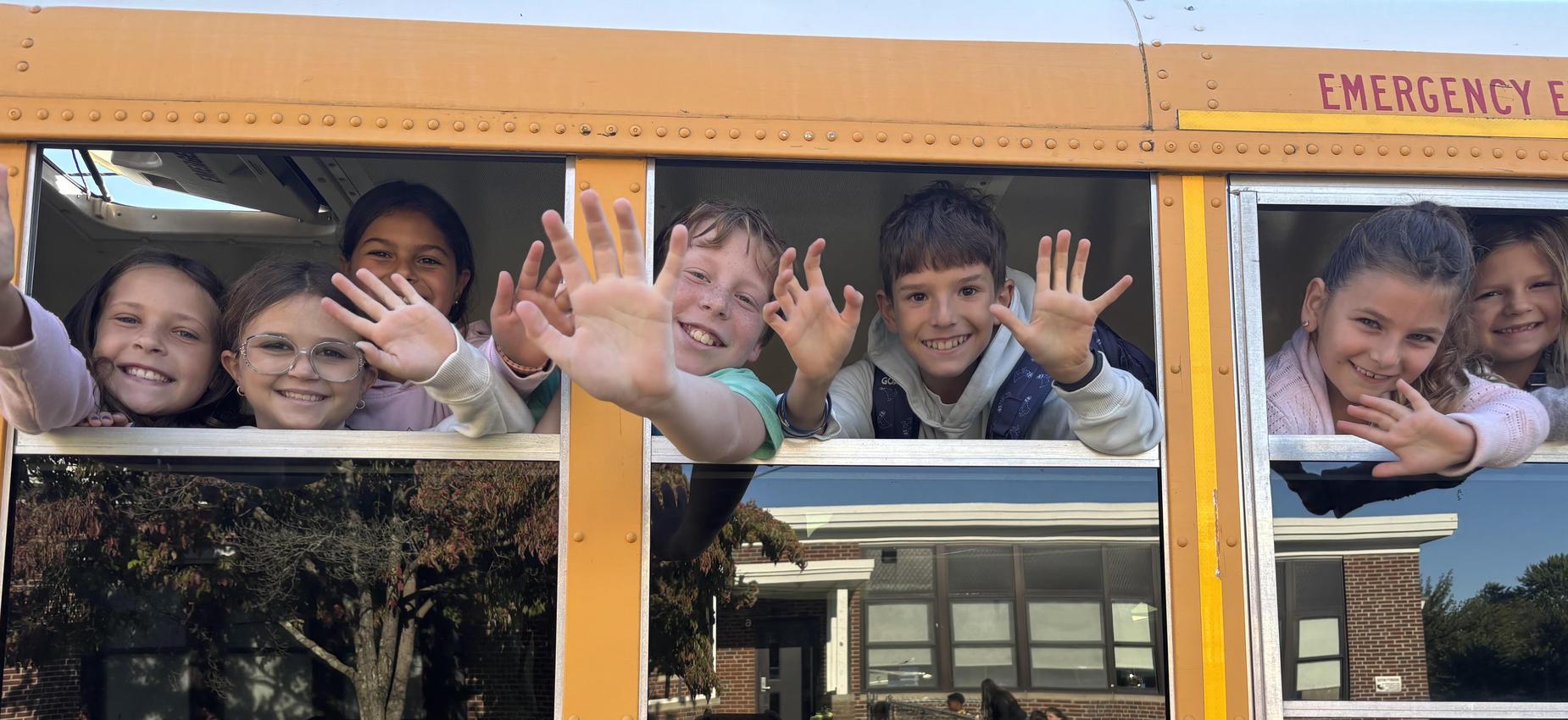 Kids waving from school bus on their first day of school