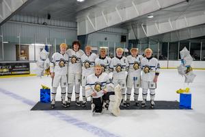 7 hockey players in a row with the goalie in front in gear between two balloon columns