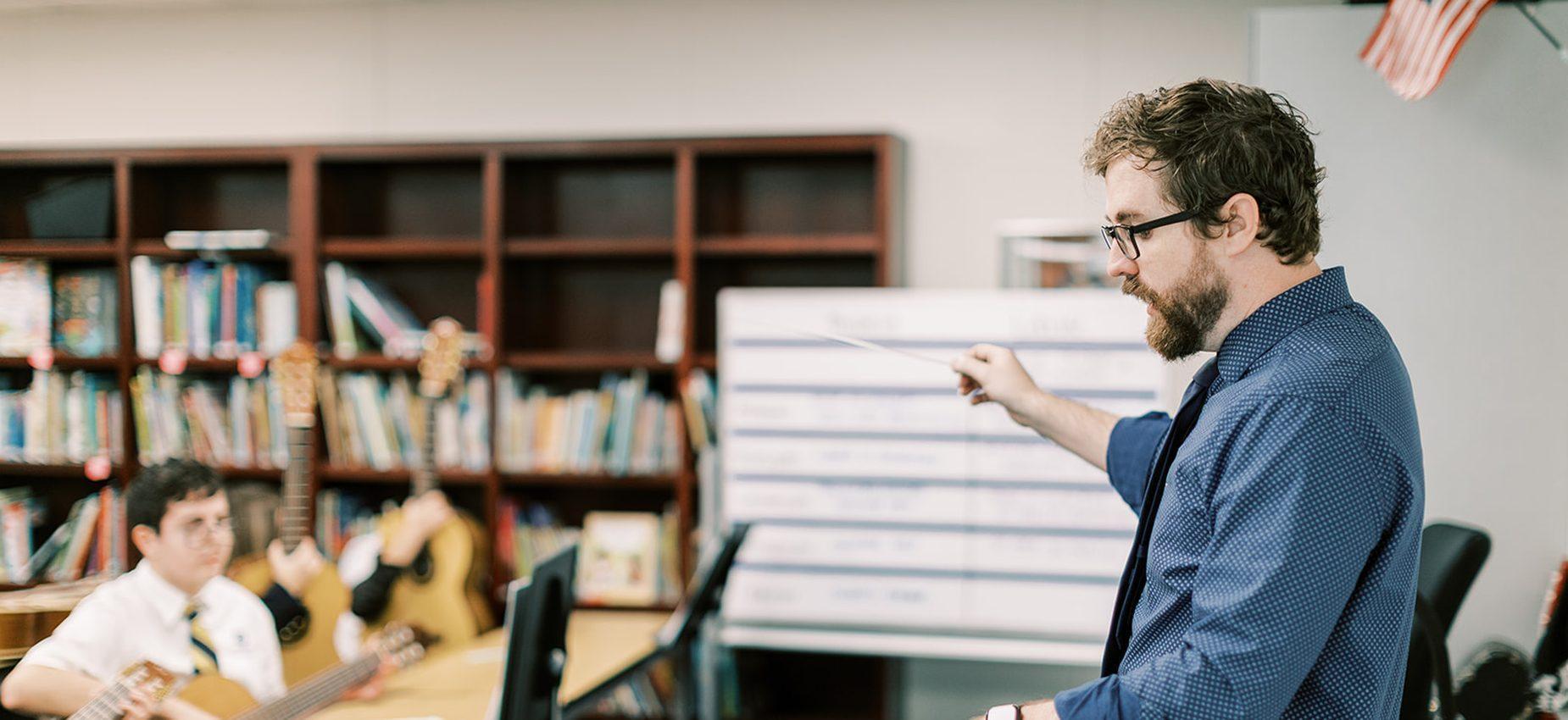 A music teacher leads a guitar lesson in the library at Plainview Classical Academy