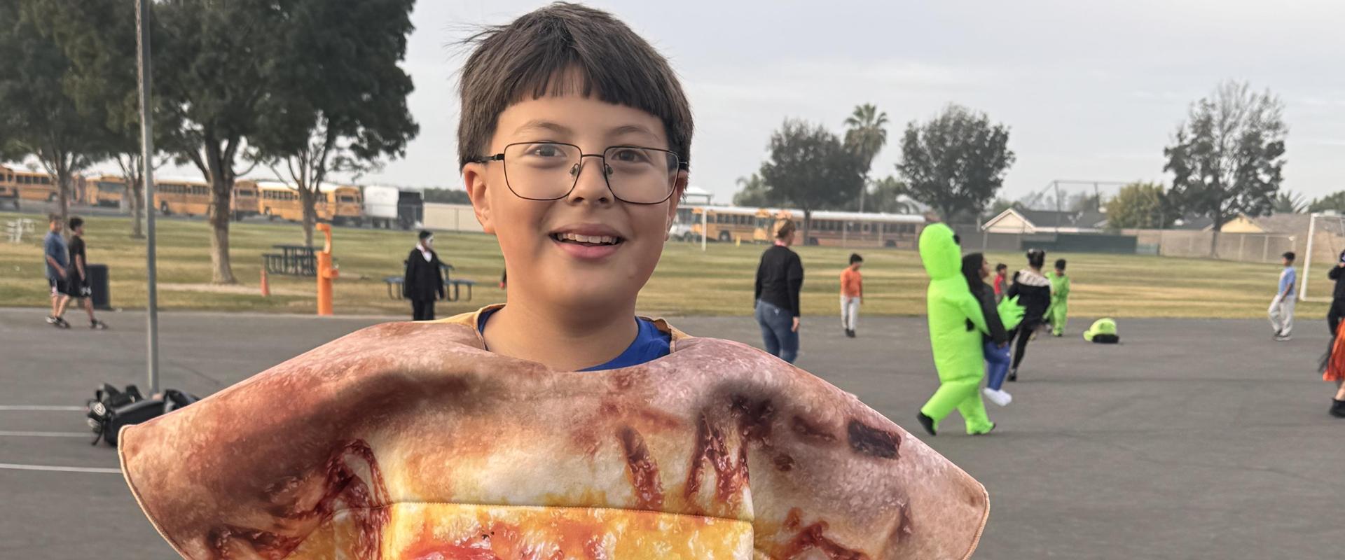 Child wearing a pizza costume, holding it up.