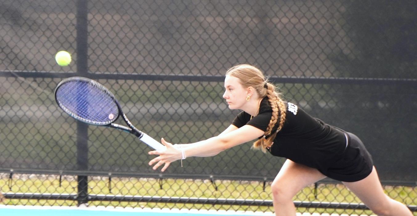 A tennis player reaches for a return.