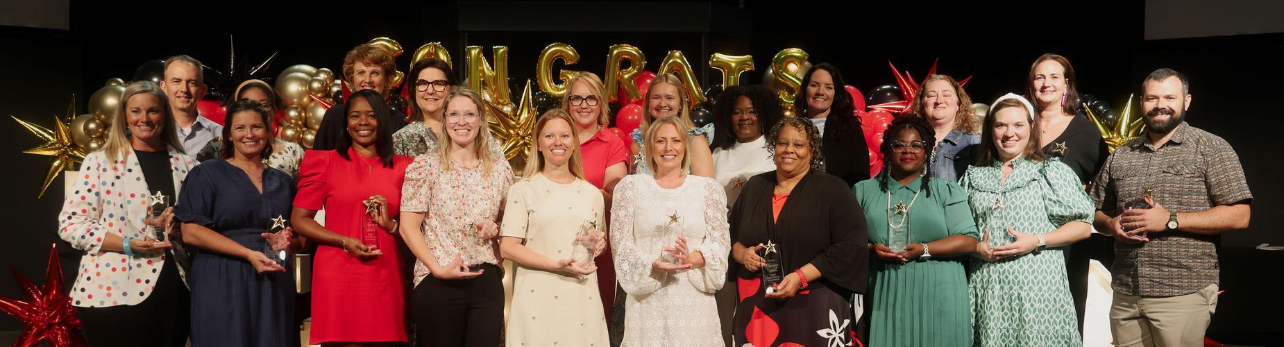 Group of award winners posing together with trophies at a celebration event.