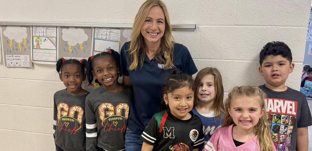 adult woman standing with 6 kids smiling