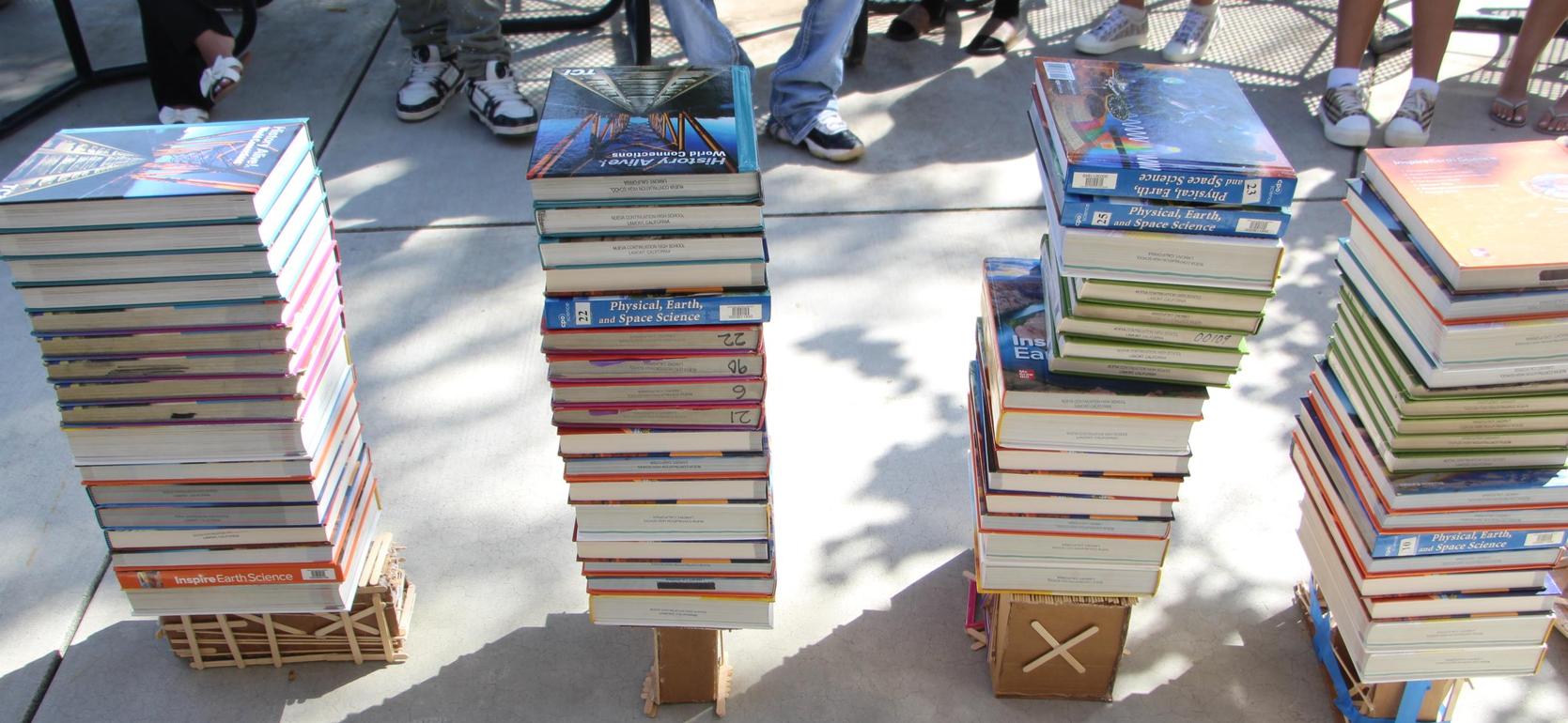 Three stacks of books arranged on a concrete surface, with bases made of cardboard.