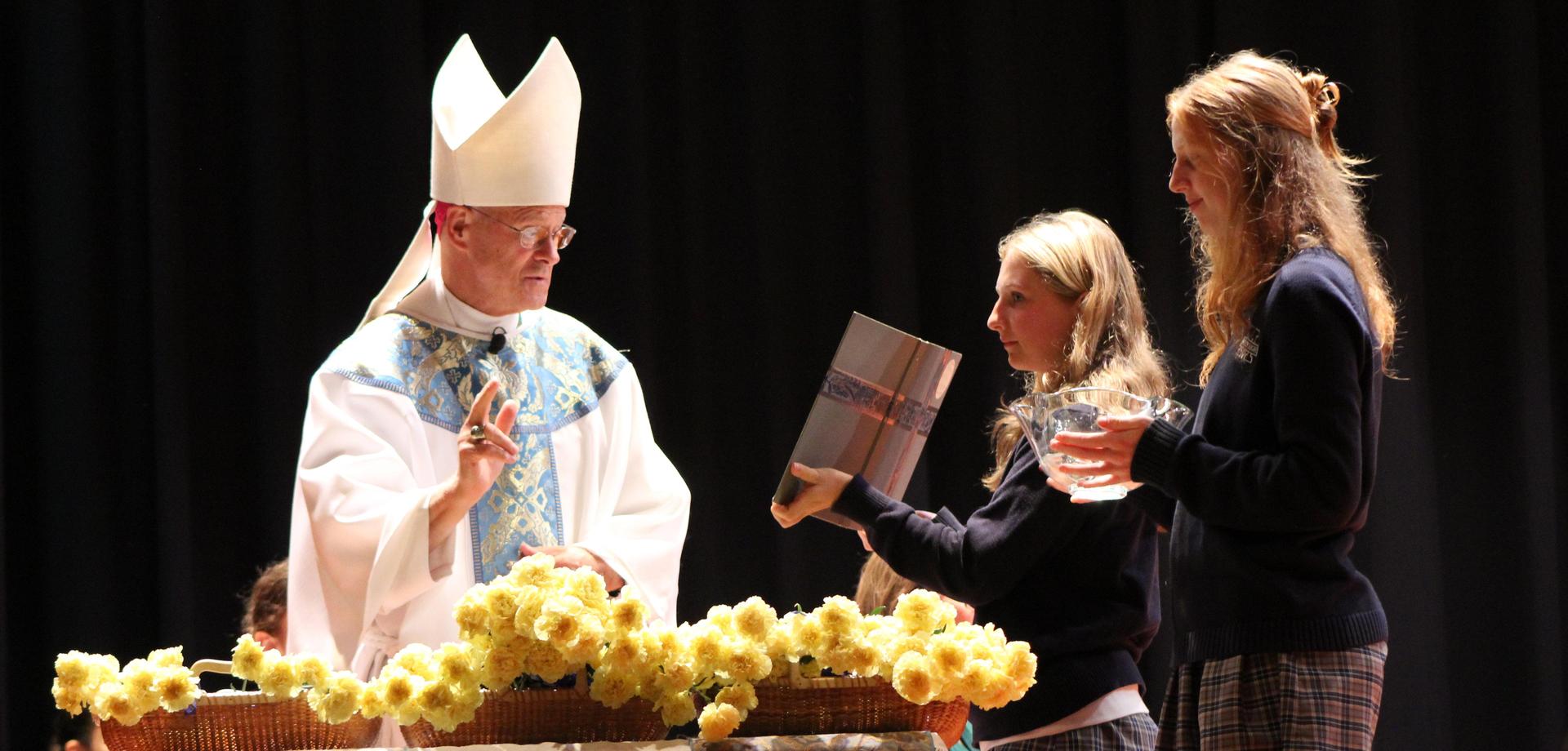 A ceremony with a priest and two participants holding a book and a bowl.