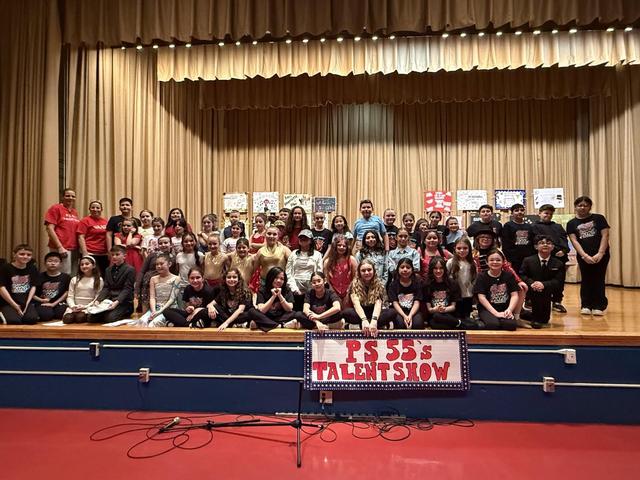 Large group of students on stage for a talent show with a decorated backdrop.