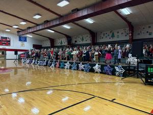 A wide view of a holiday performance with a cheering crowd and decorative snowflakes on display.