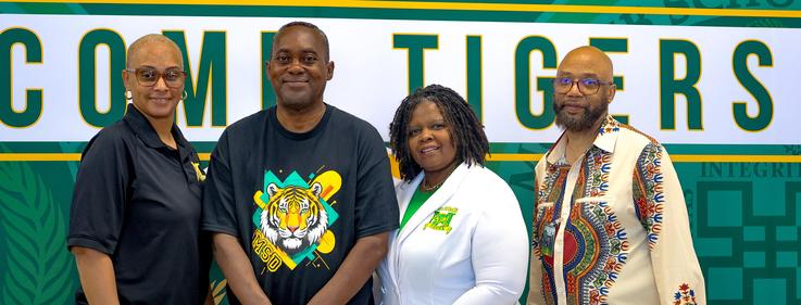 Four people posing together, wearing colorful shirts and smiling at the camera.