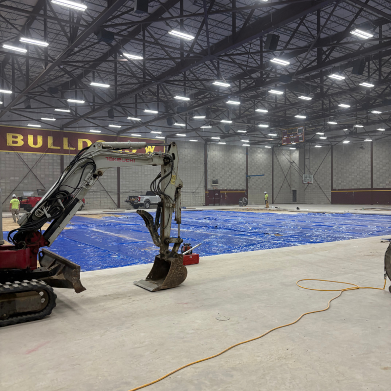 Construction equipment and blue tarp prepping for concrete pour at WAC Fieldhouse