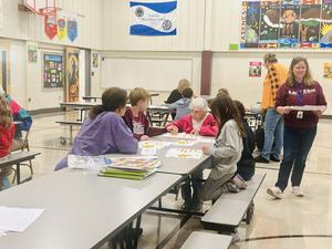 Elementary students and senior citizens working on a project in the multi-purpose room.