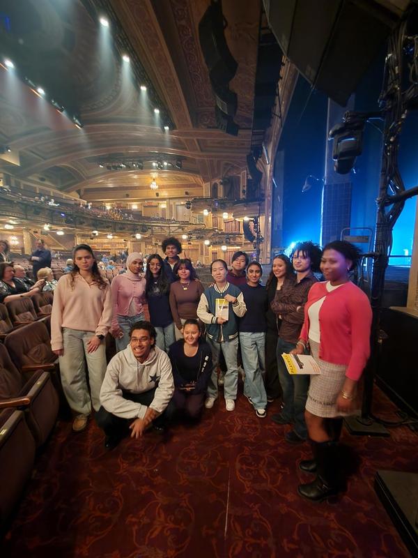 Group of people posing together in a theater with ornate architecture.