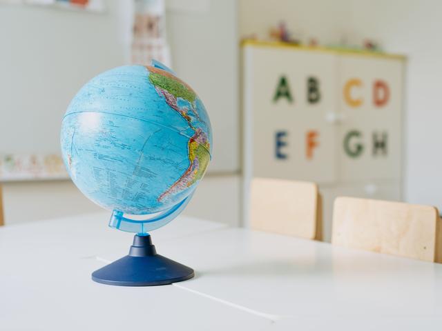 Globe on a table in a classroom with alphabet letters on the wall.