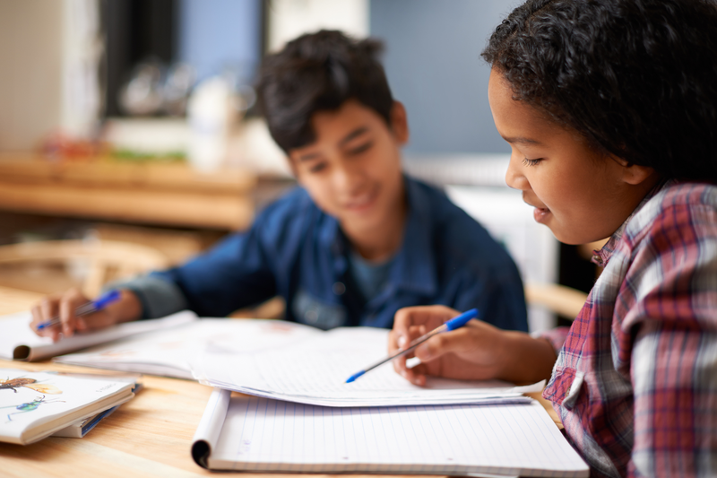 Child notepad and pen in classroom for learning education and talking for grades and study diverse kids children and help with smile and books for stationery write and childhood for school