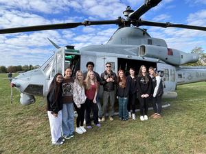 Image of students pose with chopper pilot after listening to his experiences