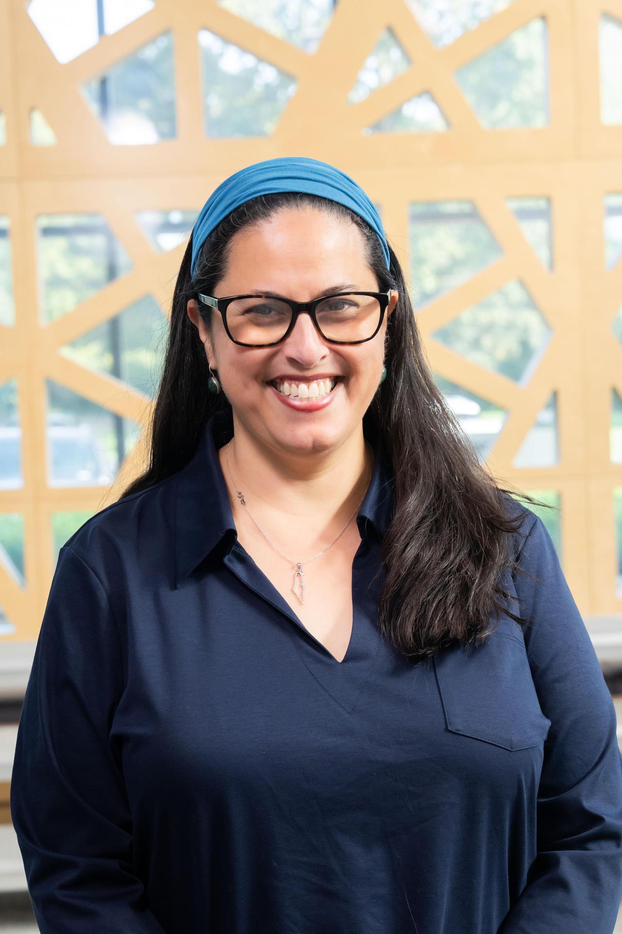 Gussie Singer with glasses and blue blouse and light blue headband smiling