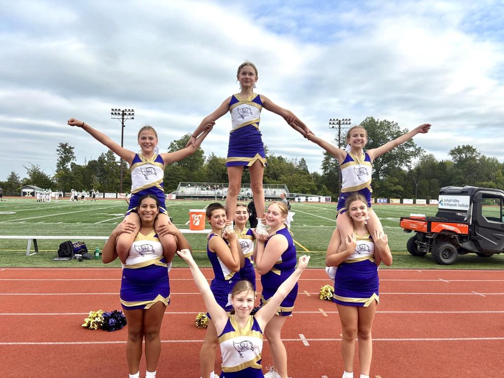 Cheerleaders in a pyramid on the track at the stadium.