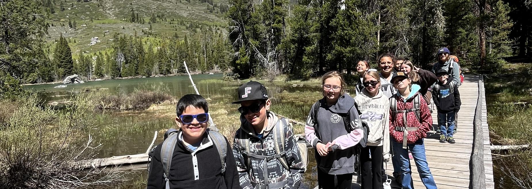 Group of kids walking on a wooden path next to a lake.