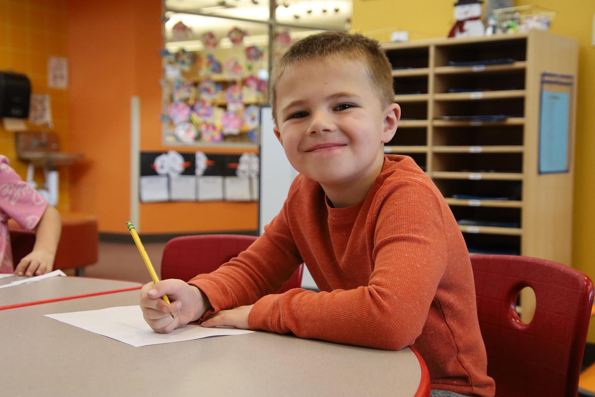 elementary school boy smiling for the camera in a classroom