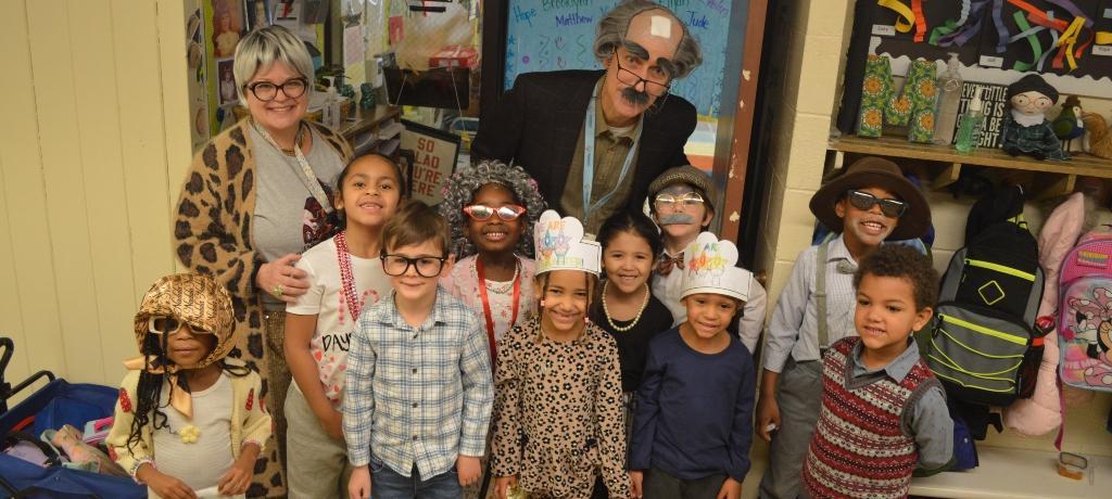 Kindergartners dressed in gray wigs and canes pose for the camera