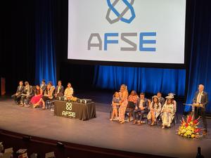 Graduation event on stage with speakers, graduates, and decorations.