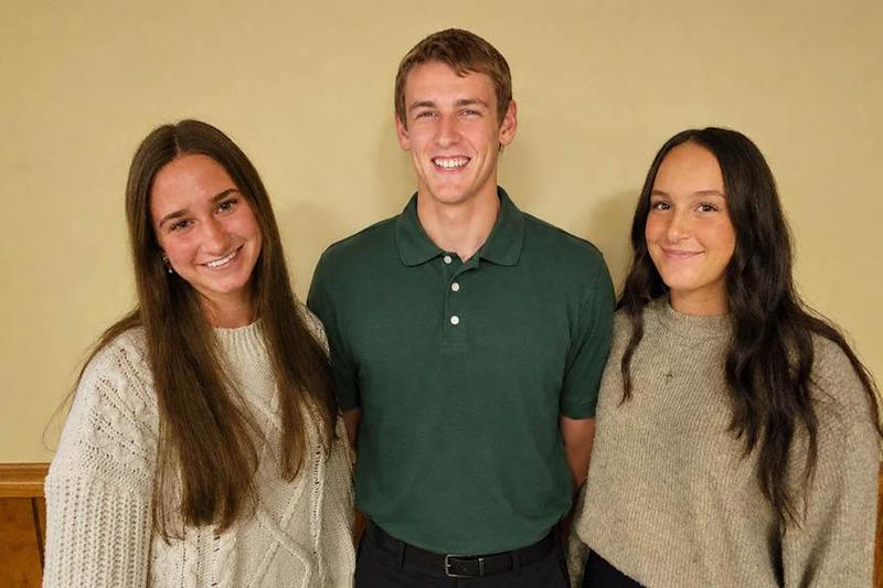 Three students stand together with large smiles