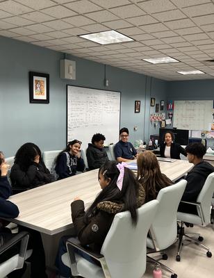 A group of young people seated around a conference table in a meeting.