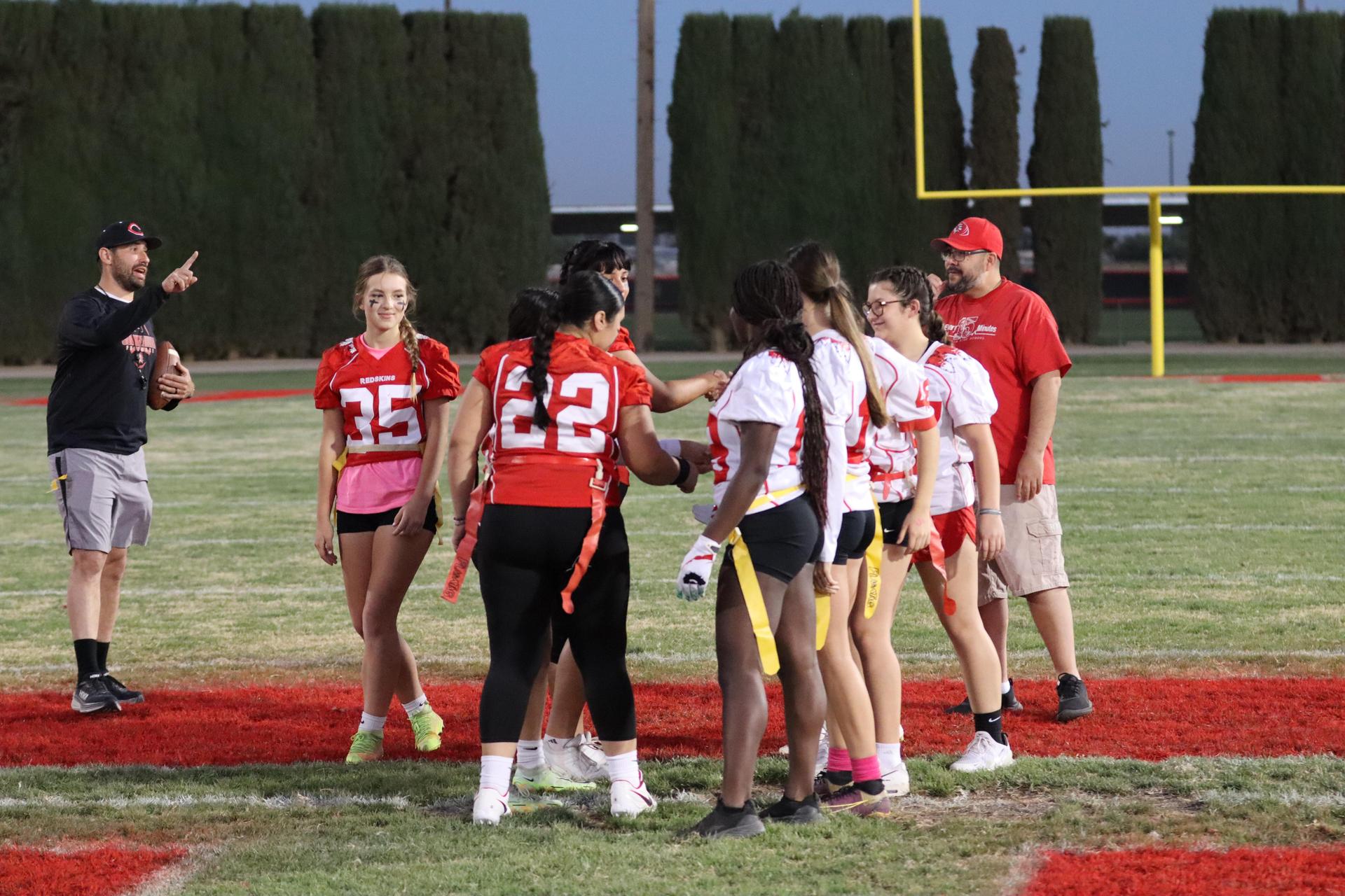 players, cheerleaders, and officials preparing for the powderpuff football game